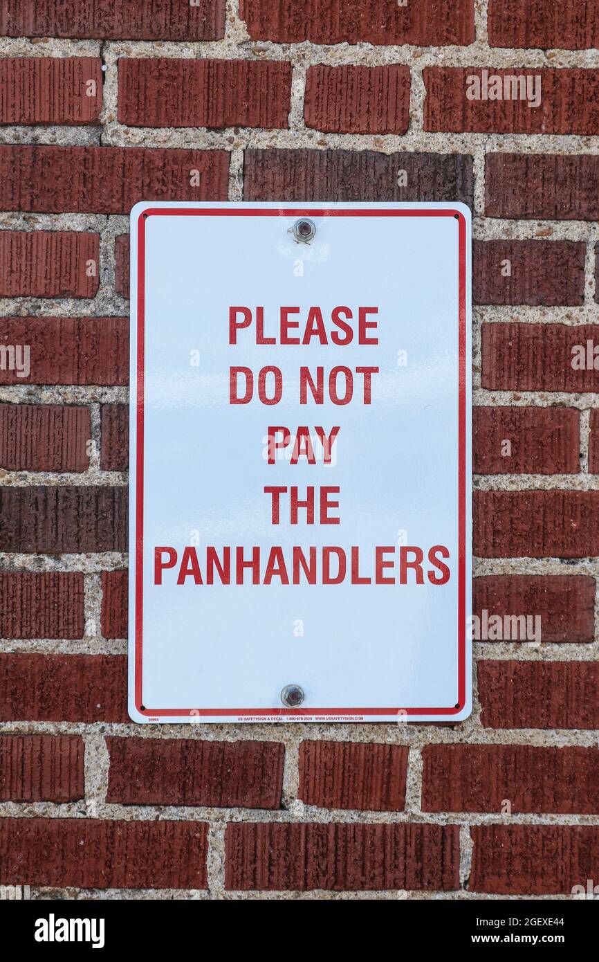 Sign that says please do not pay the panhandlers posted on brick wall - close-up Stock Photo