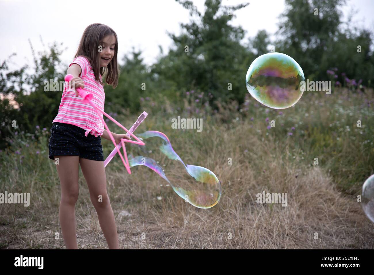 A little girl in nature plays with big soap bubbles Stock Photo - Alamy