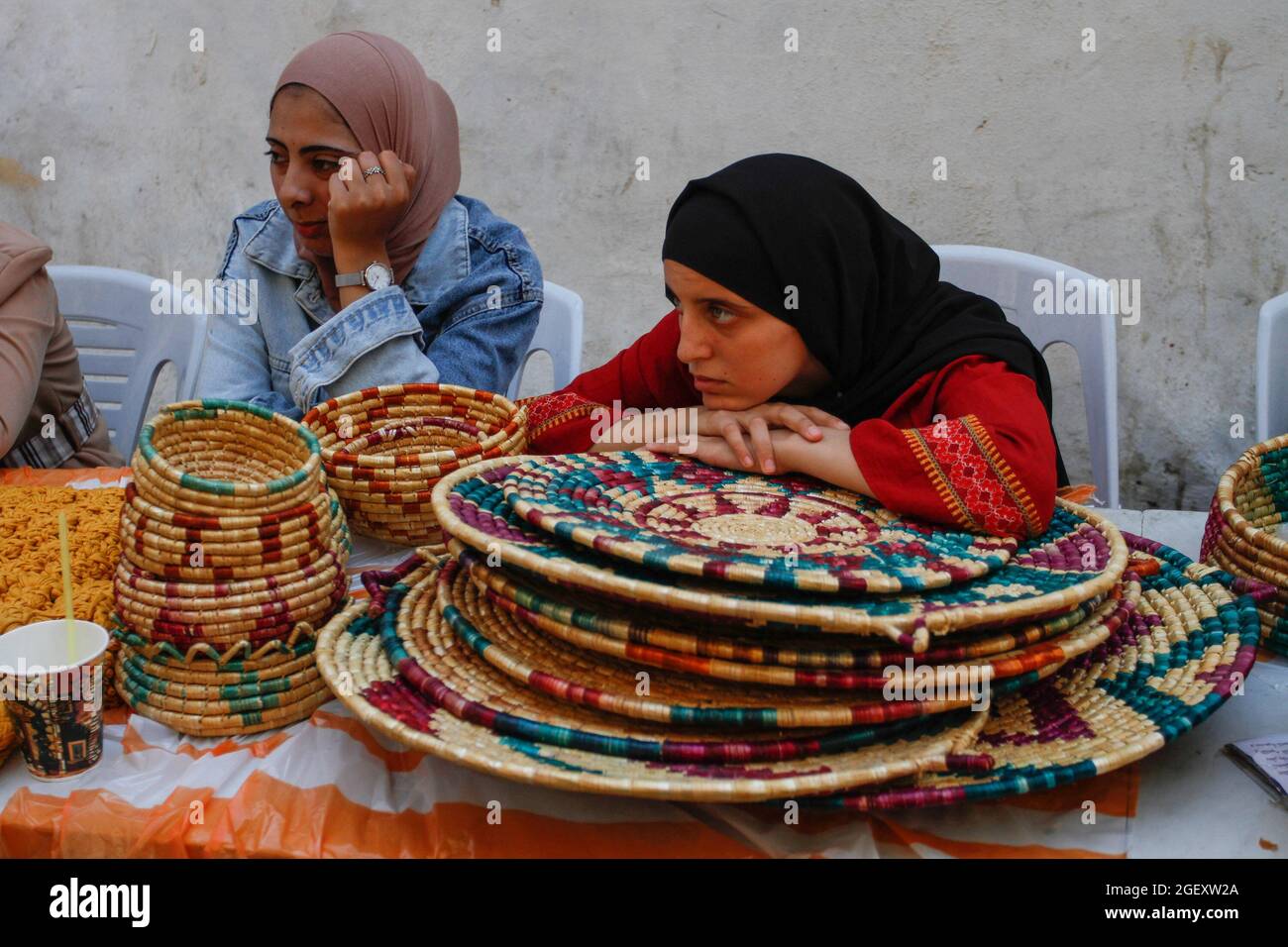 Nablus, Palestine. 21st Aug, 2021. Palestinian women attend to an exhibition of Palestinian heritage on the occasion of the Day of Palestinian Customs and Traditions in the West Bank city of Nablus. Palestinian fashion is the traditional clothing often worn by Palestinians and foreign travelers to Palestine in Palestine. The nineteenth and early twentieth centuries commented on the rich variety of costumes worn by peasants or village women. Richly and creatively embroidered handcrafted garments. Credit: SOPA Images Limited/Alamy Live News Stock Photo