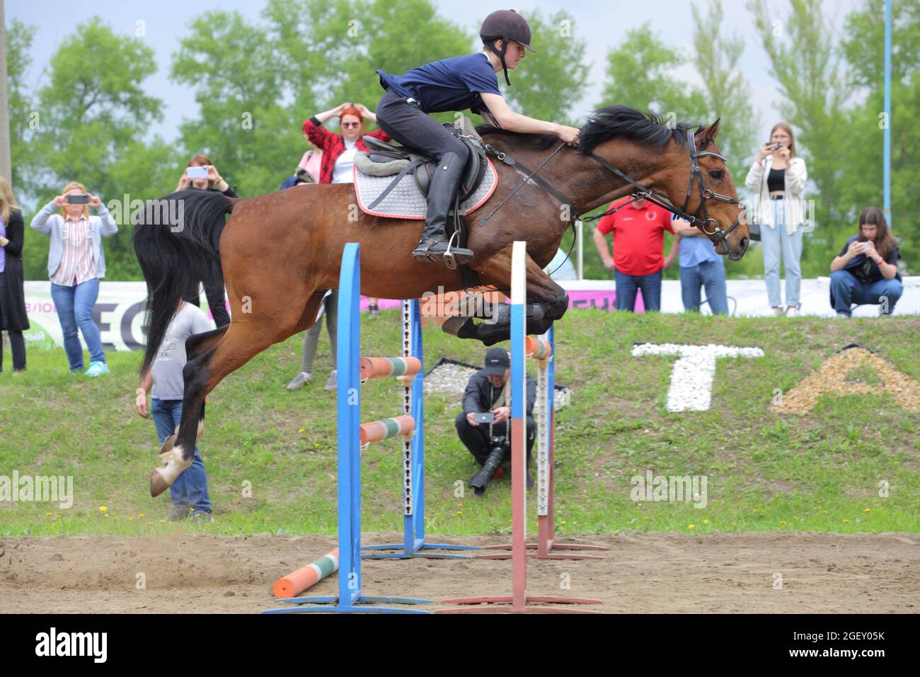 Young sports girl jumping obstacle with bay horse Stock Photo