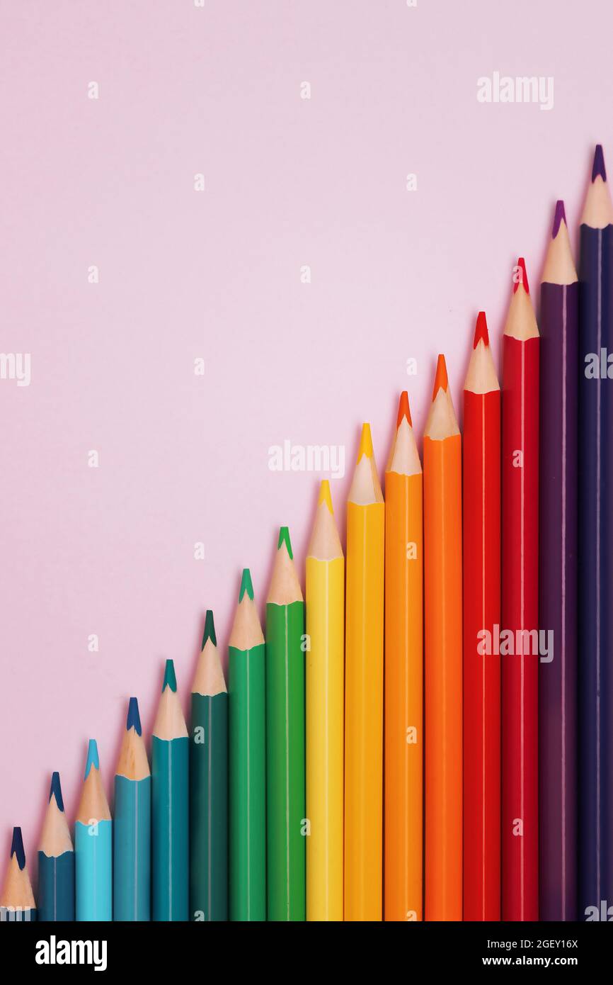 Colored pointed pencils lie on a pink background with space for copying ...
