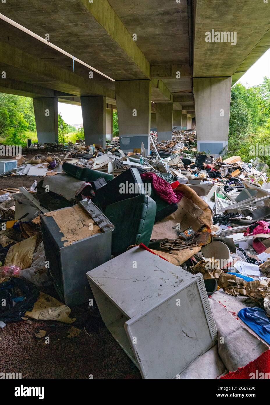 A huge amount of illegal fly tipping waste from construction sites and households dumped under the M8 viaduct, Glasgow, Scotland Stock Photo