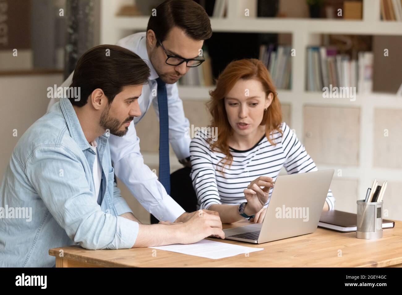 Three caucasian colleagues using laptop discussing collaborative on-line project Stock Photo
