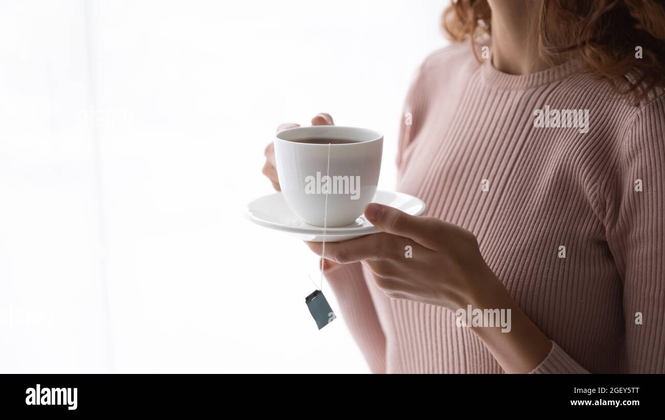 Closeup female hands holding cup with teabag inside Stock Photo