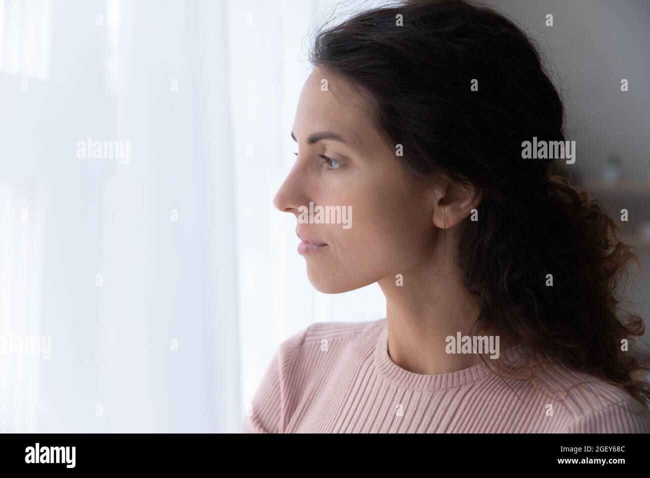 Closeup face of serious Hispanic woman looks out the window Stock Photo