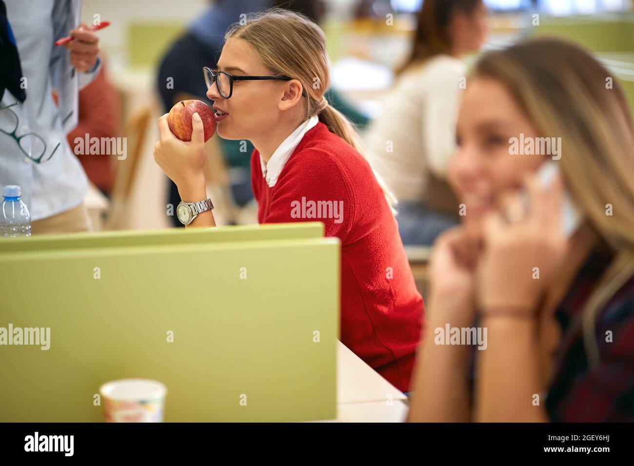 Female student enjoying a snack in a break of the lecture in the university classroom. Smart young people study at the college. Education, college, un Stock Photo