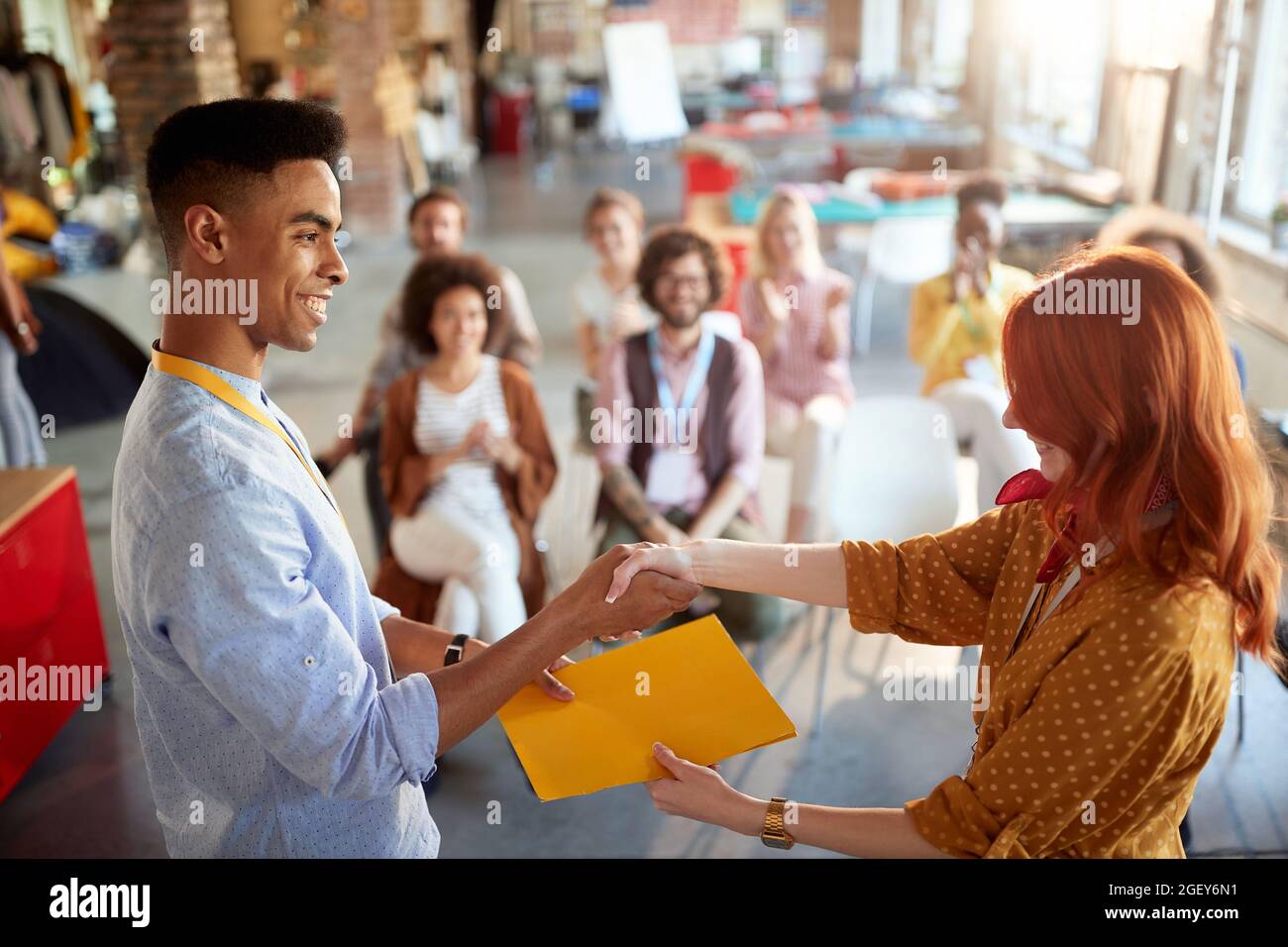 young redhead female congratulate to a student for successful attending business seminar, giving him certificate in folder. selective focus image. Stock Photo
