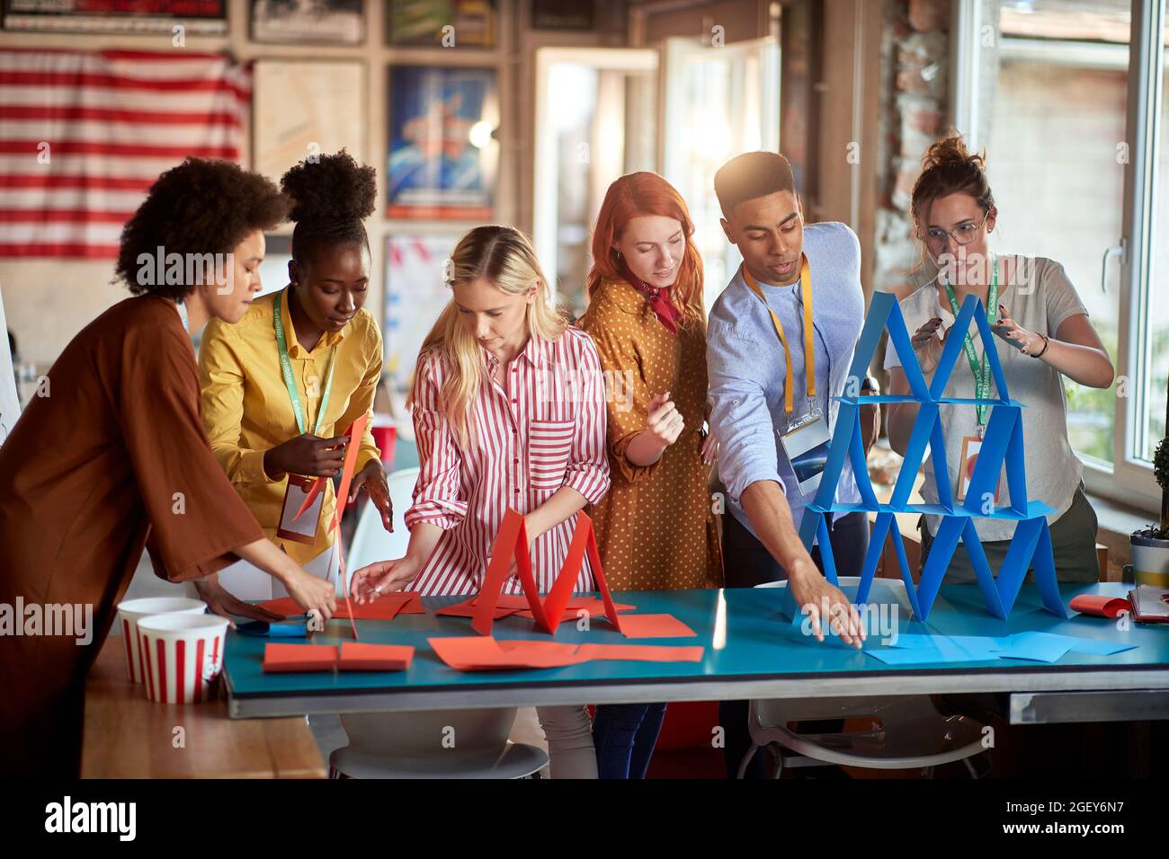 two groups of employees making paper towers at work, separated in different competitive multiethnic teams. Stock Photo