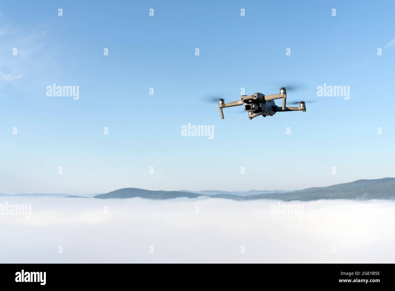 flying a quadrocopter helicopter drone in the air, in a clear blue sky ...