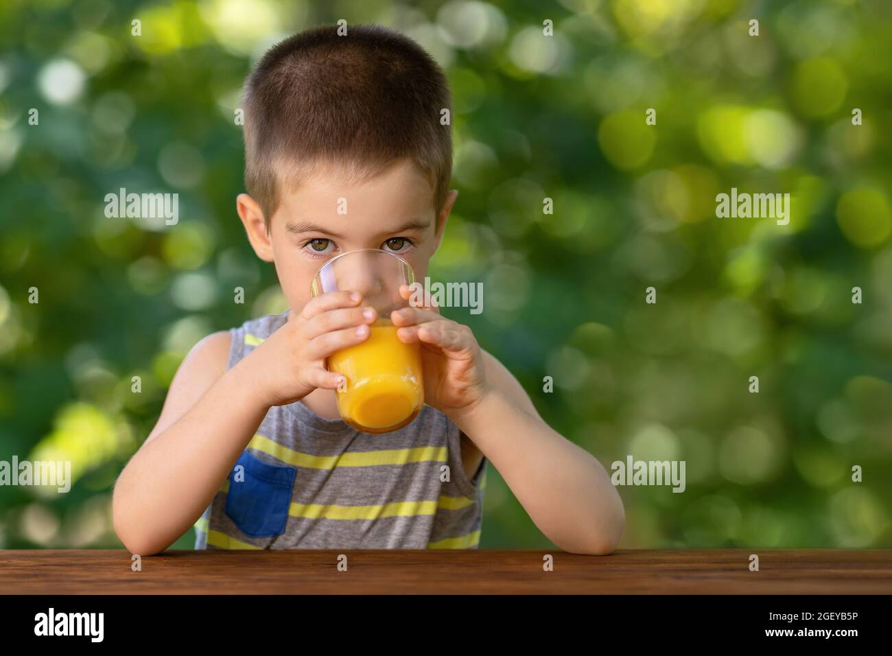 little boy drinking orange juice from glass Stock Photo