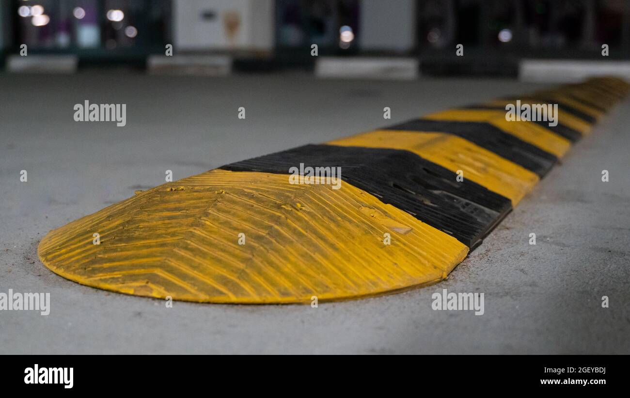 Traffic safety speed bump on an asphalt road in a parking area. Speed bumps (or speed breakers) are the common name for a family of traffic calming de Stock Photo