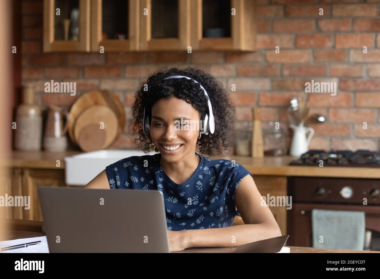 Happy African American student girl in headphones studying from home ...