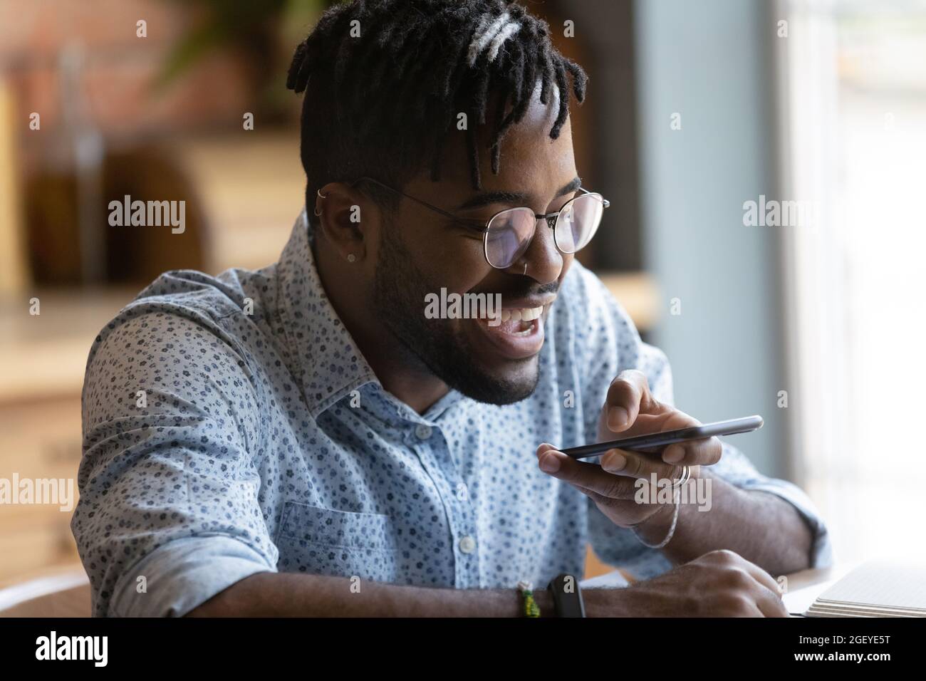 Happy millennial hipster guy using voice recognition app on smartphone Stock Photo