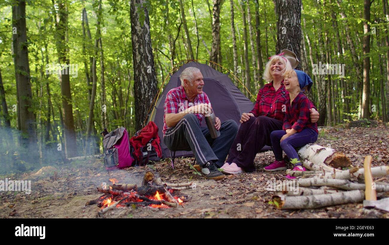 Senior grandmother grandfather granddaughter telling funny stories fairy  tales over campfire in wood Stock Photo - Alamy