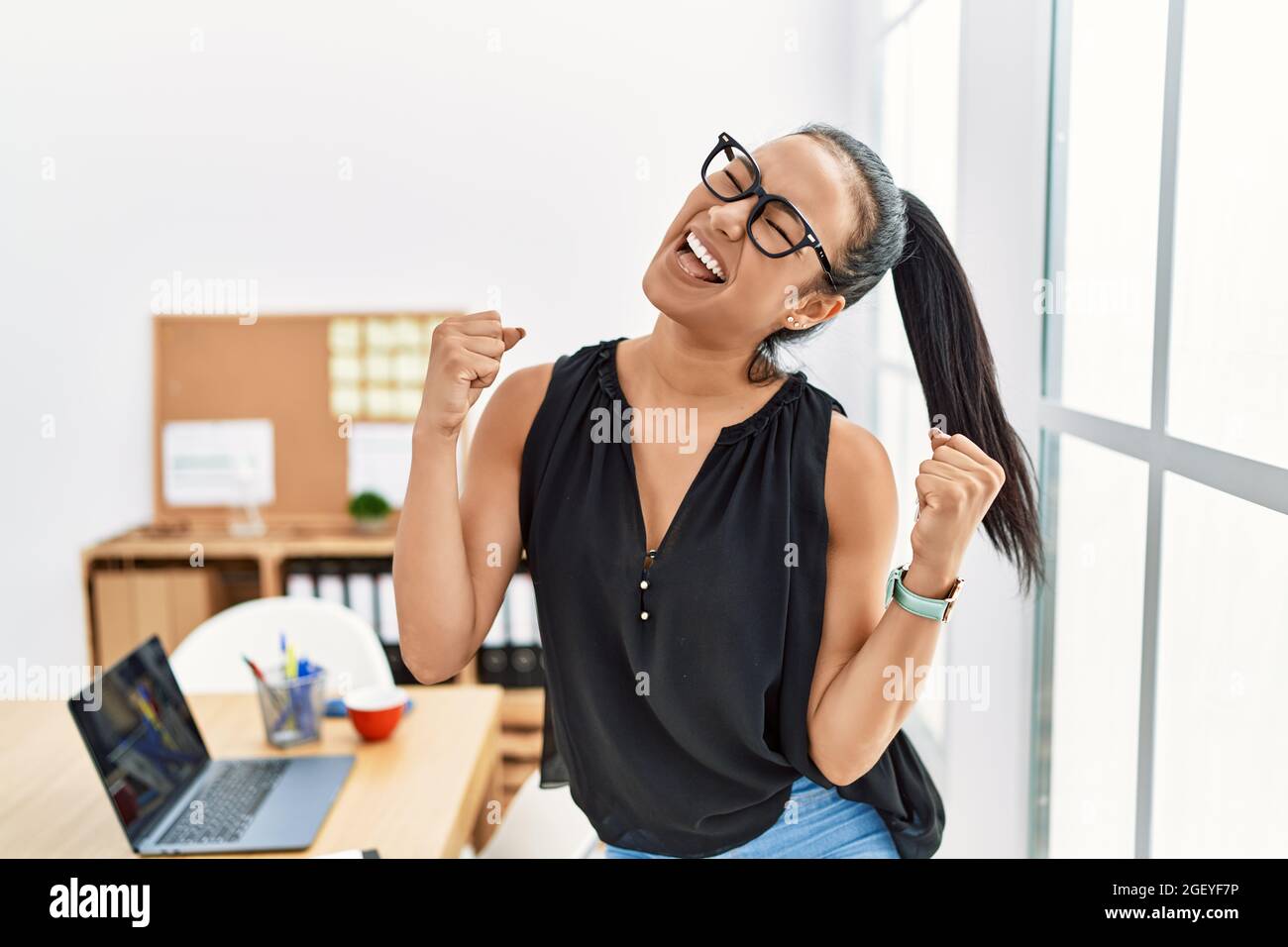 Young hispanic business woman working at the office very happy and ...