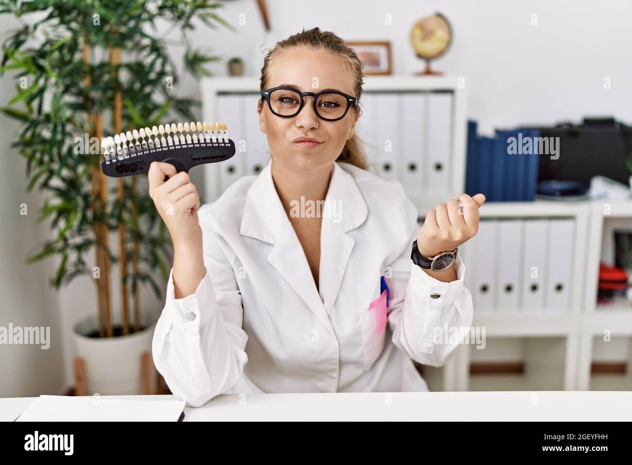 Young caucasian woman holding teeth whitening palette doing money