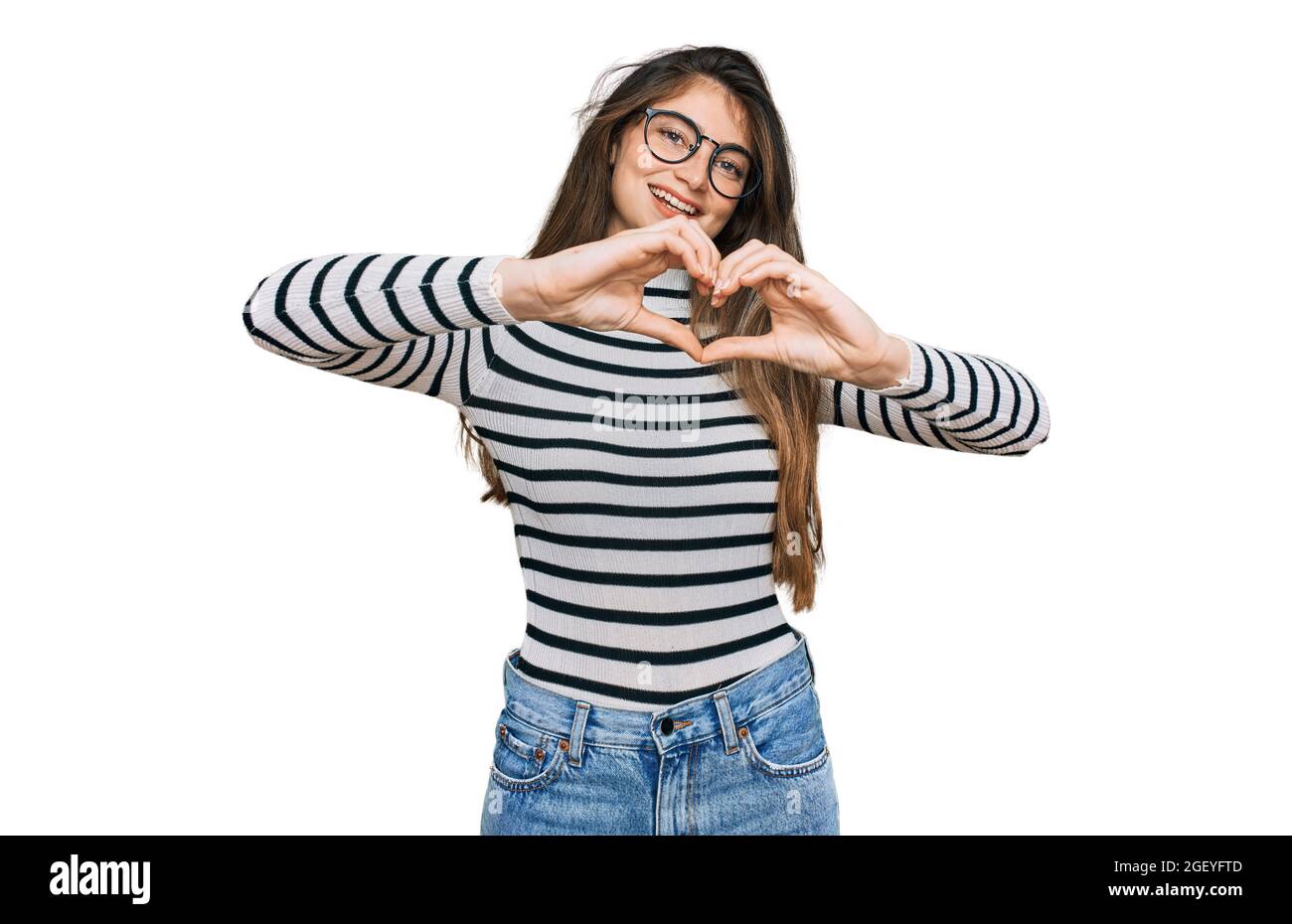 Young beautiful teen girl wearing casual clothes and glasses smiling in love doing heart symbol shape with hands. romantic concept. Stock Photo