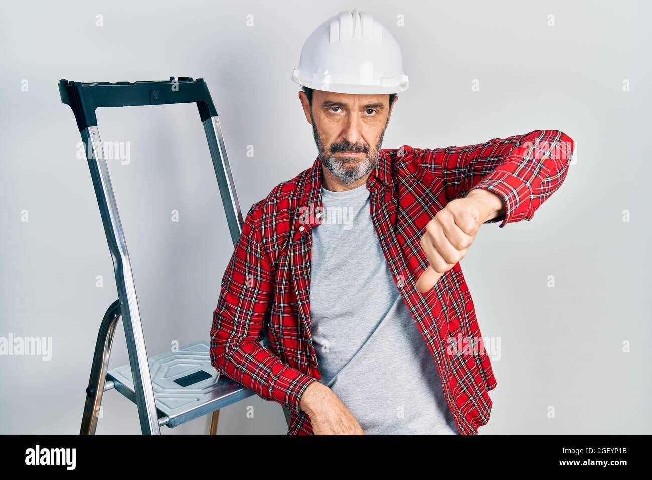 Middle age hispanic worker man using ladder with angry face, negative ...