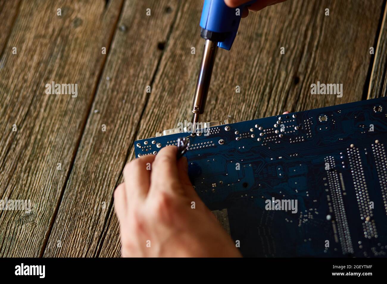 Technician or engineer is focused on repairing electronic circuit board with soldering iron. Man hands soldiers computer circuit board using soldering Stock Photo