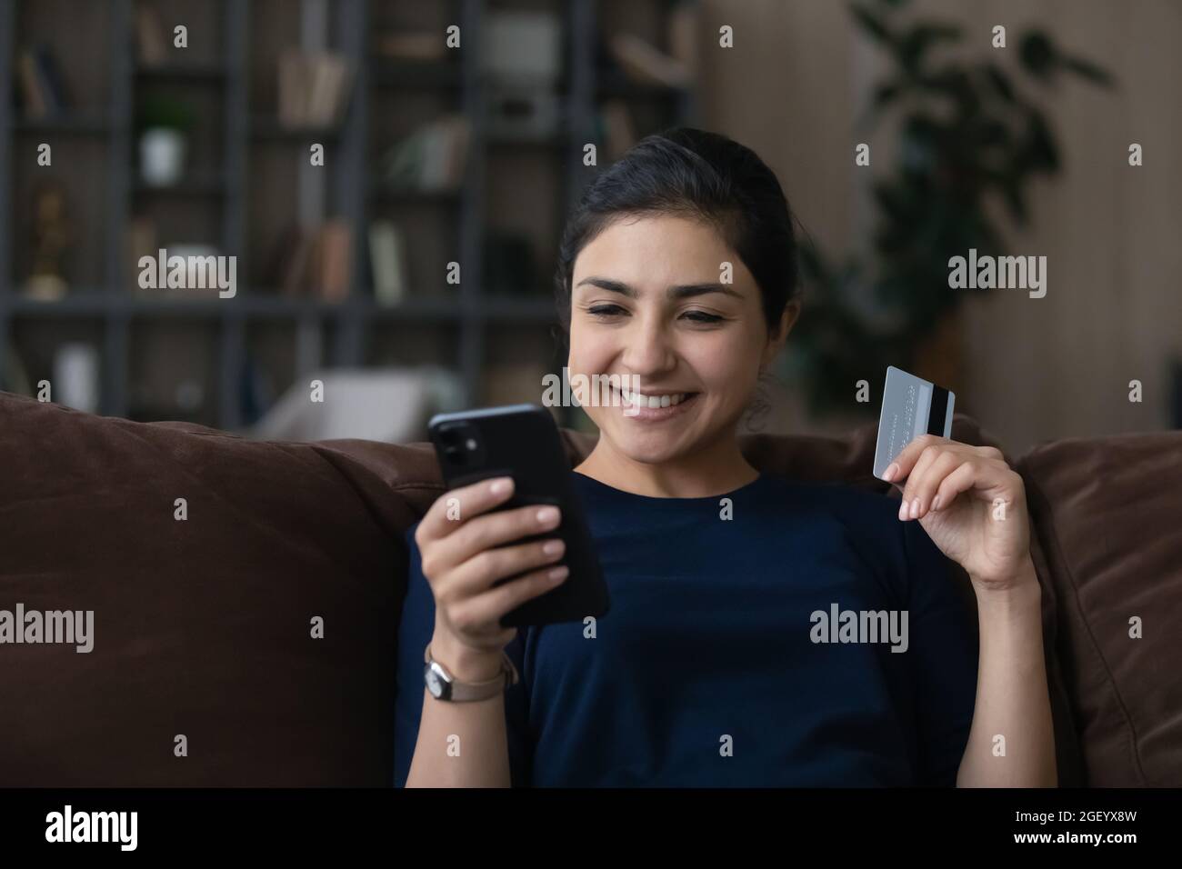 Smiling Indian female buyer shopping online on smartphone Stock Photo