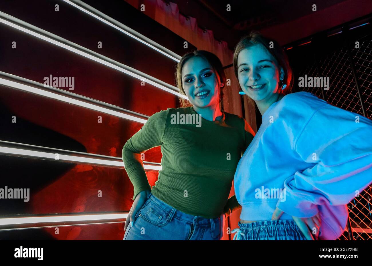 Selfie portrait of two happy best female friends, young girls with natural makeup in stylish clothes hugging each other by shoulders, having fun at di Stock Photo