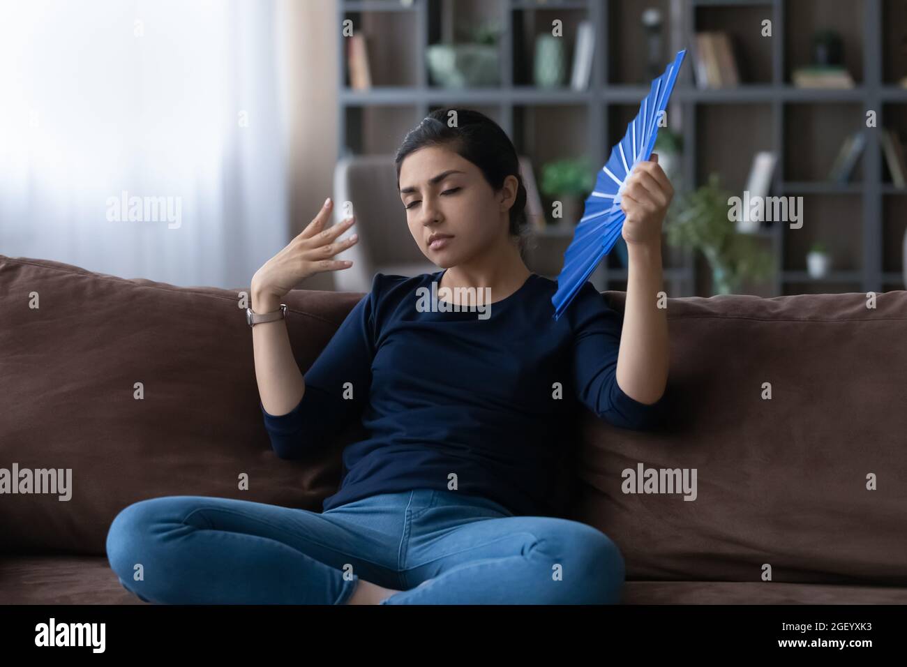 Unhappy Indian woman wave with hand fan Stock Photo