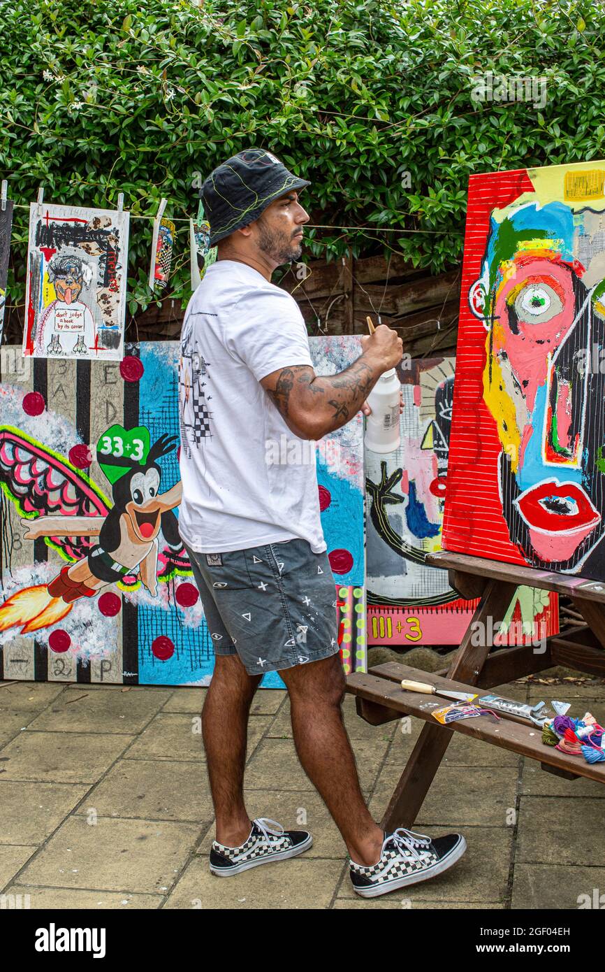 Young male artist finishing his painting on canvas standing in a garden. Stock Photo