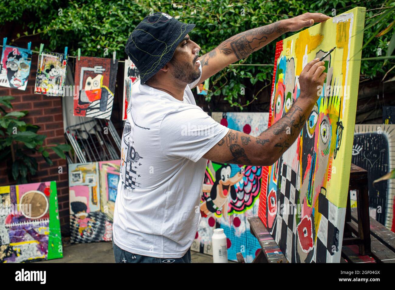 Young male artist finishing his painting on canvas standing in a garden. Stock Photo