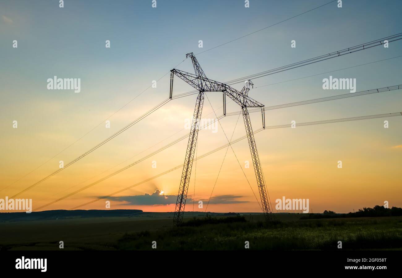 Dark silhouette of high voltage towers with electric power lines at ...