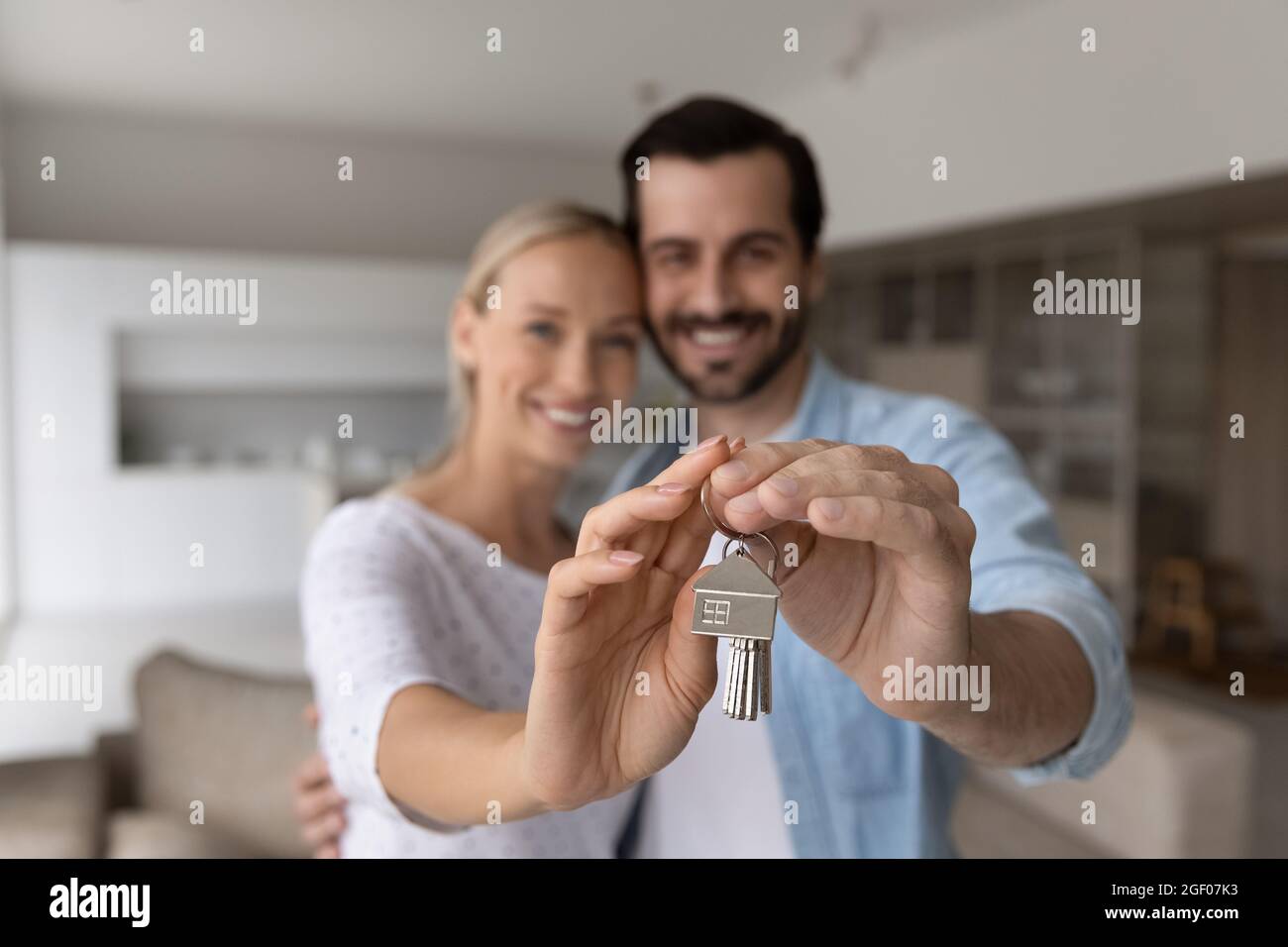 Happy proud millennial couple holding, showing keys, smiling at camera Stock Photo
