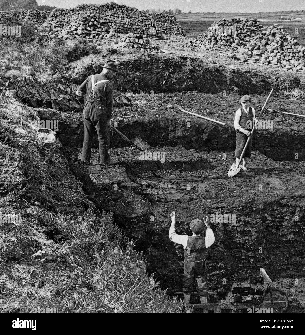 An early 20th century scene of a family cutting turf (or peat) in the blanket Bog of Allan in County Kildare, Ireland Stock Photo