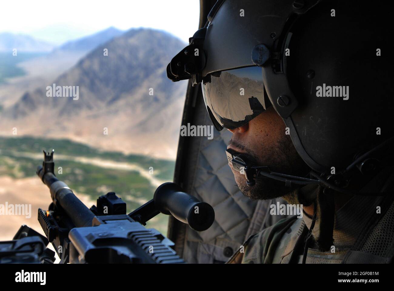 Sgt. Shawn Adams, gunner on a CH-47, keeps watch on the mountains in Uruzgan province, Afghanistan, May 12, 2013. The Chinooks, operated by members of Bravo Company, 2nd Battalion, 104th Aviation Regiment from the Connecticut and Pennsylvania Army National Guard , have played a vital part in the mission in Afghanistan since their arrival in Dec. 2012 by performing resupply, retrograde, and planned missions. (U.S. Army photo by Sgt. Jessi Ann McCormick) Stock Photo