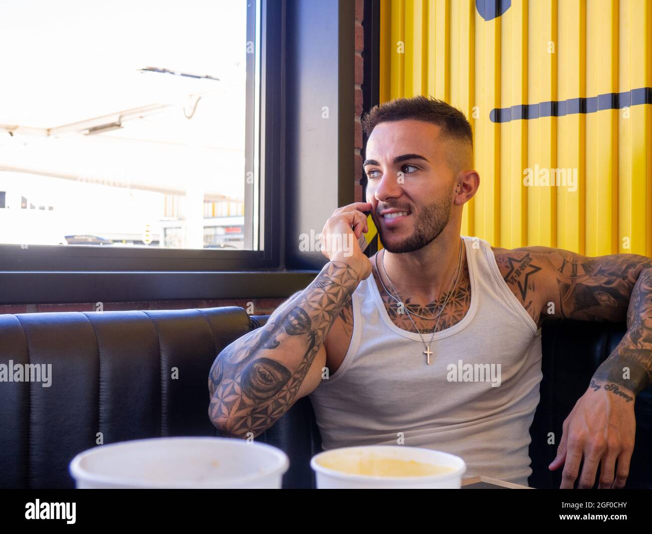 A cheerful attractive Spanish man with tattoos talking on the phone in a restaurant Stock Photo - Alamy
