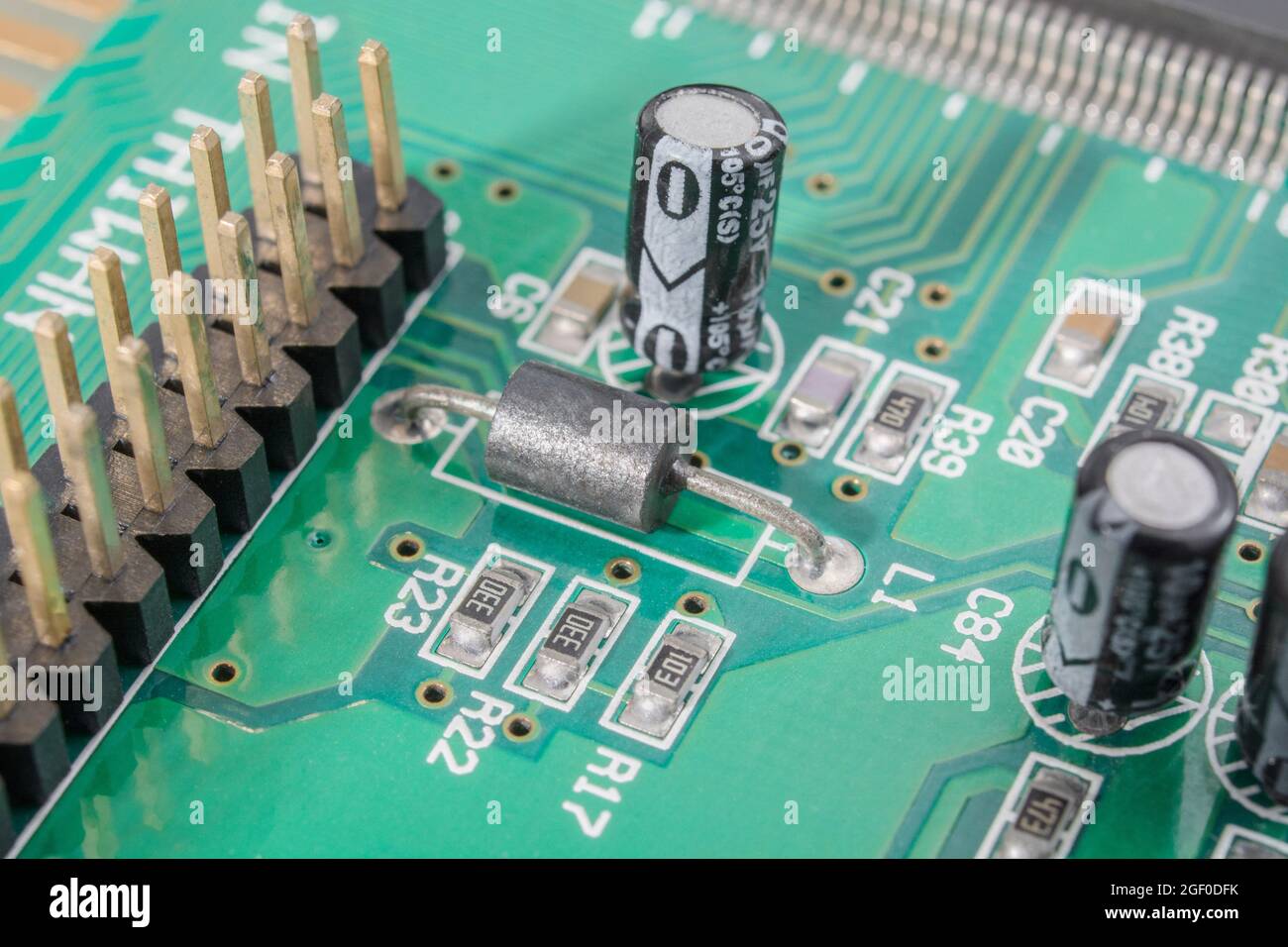 Close up of resistor-like through-hole black ferrite bead component on circuit board + smaller oblong SM / surface mount resistors. Stock Photo