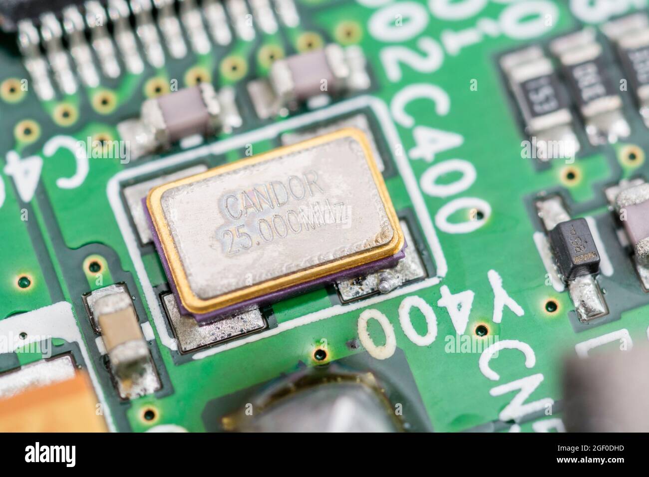 Close up macro of SM / surface mount metallic crystal oscillator on a pcb circuit board. Rated at 25Mz and made by Candor (Chinese company). Stock Photo