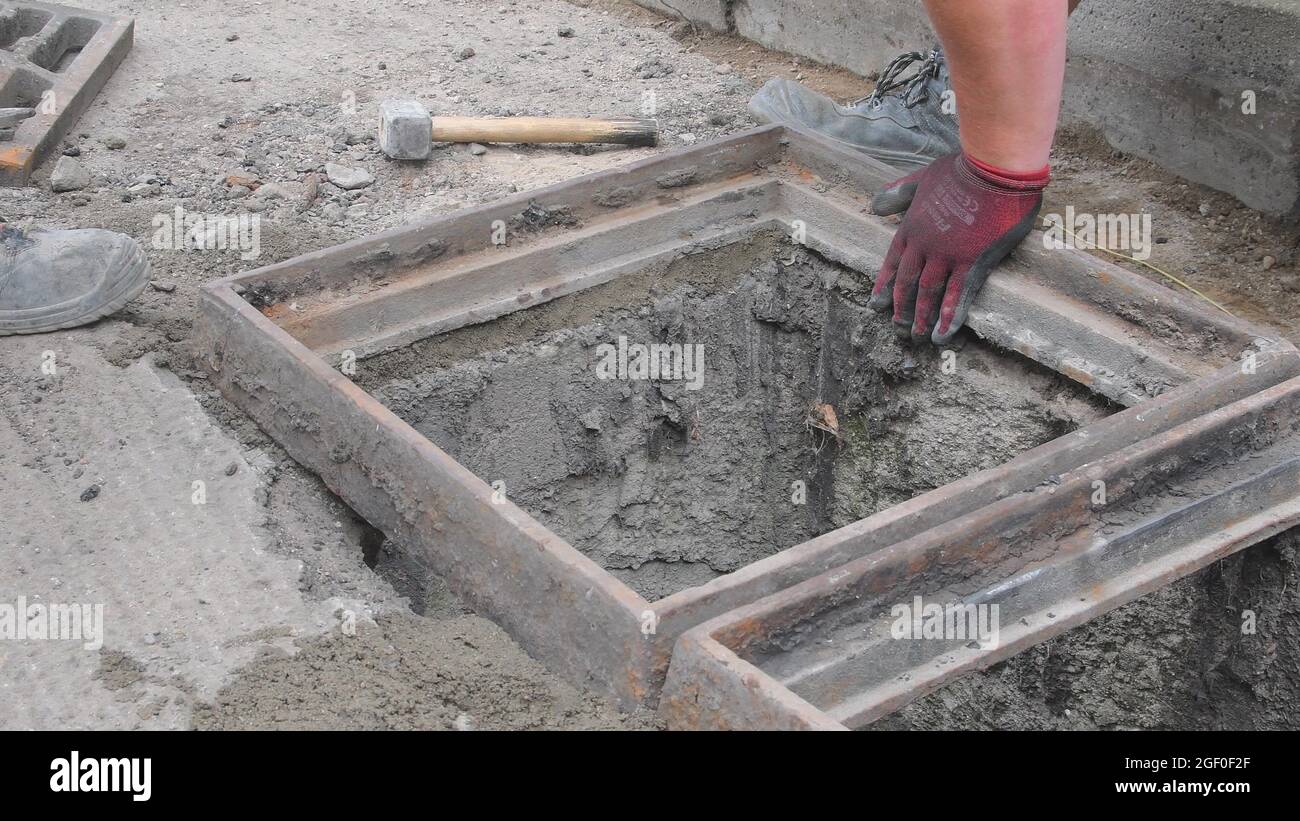 Workers making base for sewer grill. Bulding worker using water level. Bulding worker concept Stock Photo