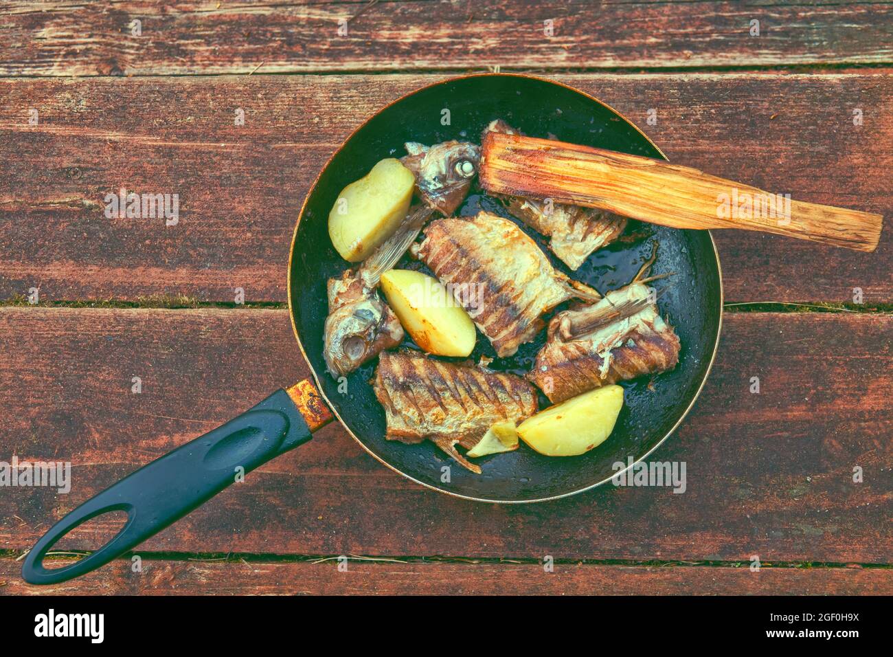 Field food. Fried fish and jacket potato in a frying pan with a