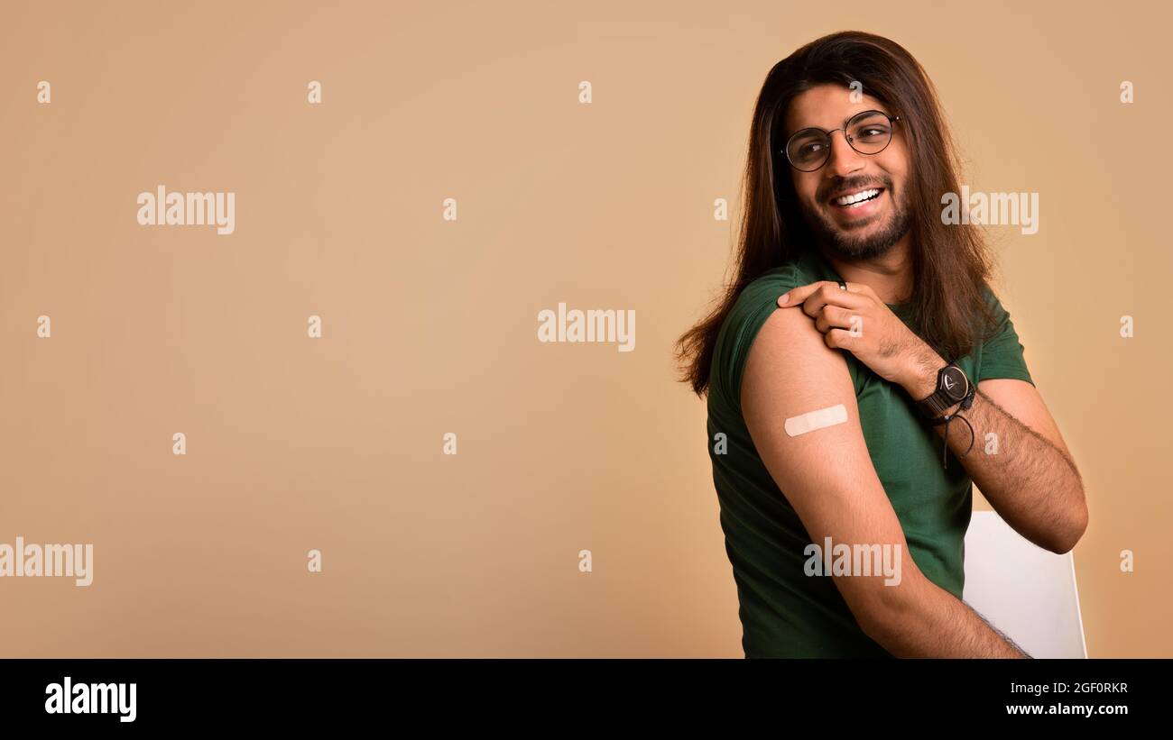 Healthy middle-eastern man showing medical band, got vaccinated Stock Photo