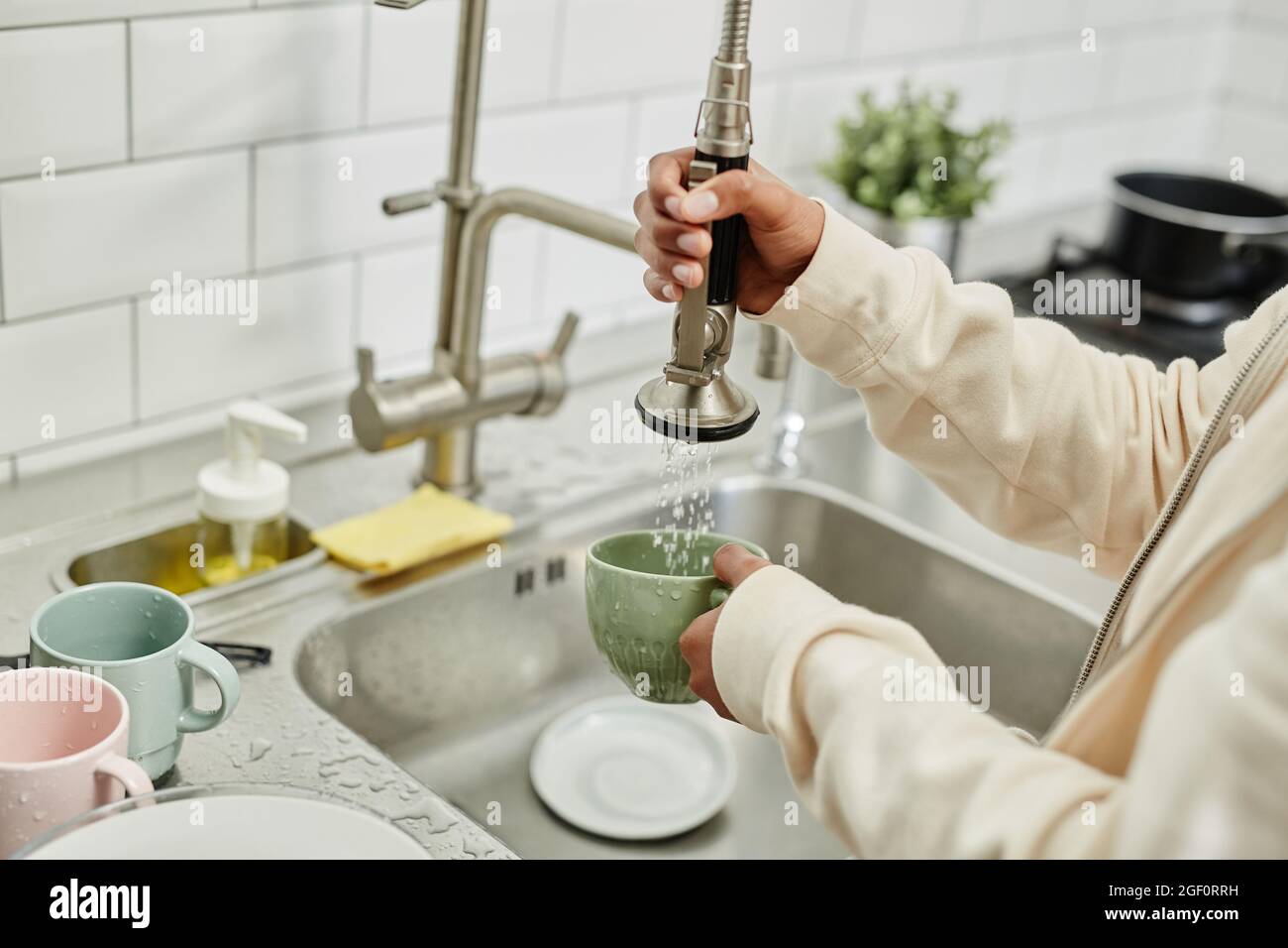 Close up of young African-American woman washing dishes at home while doing chores on weekend, copy space Stock Photo