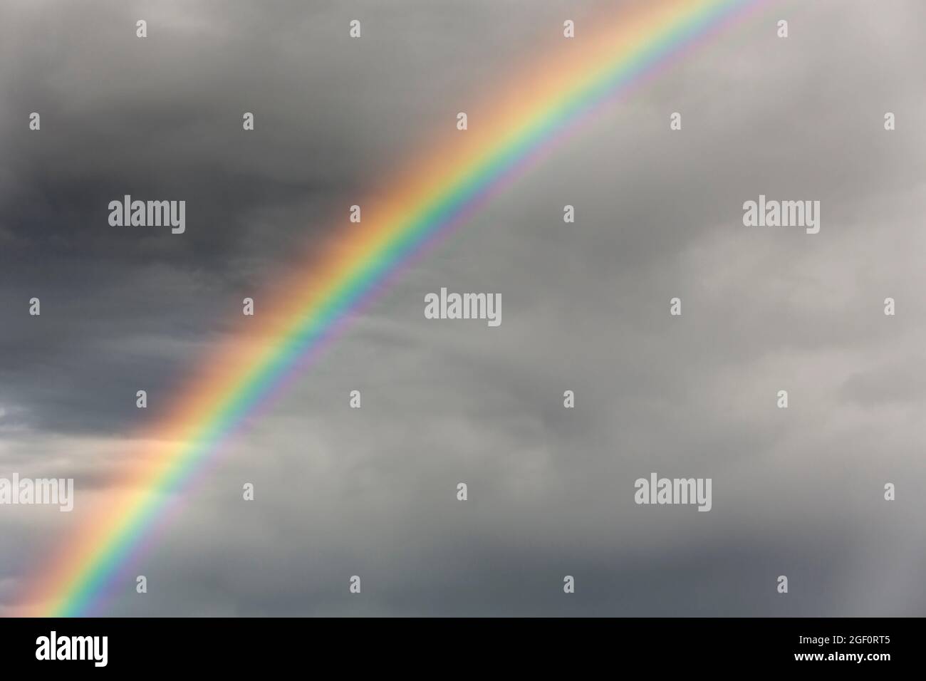Colourful rainbow in a dark grey stormy sky Stock Photo