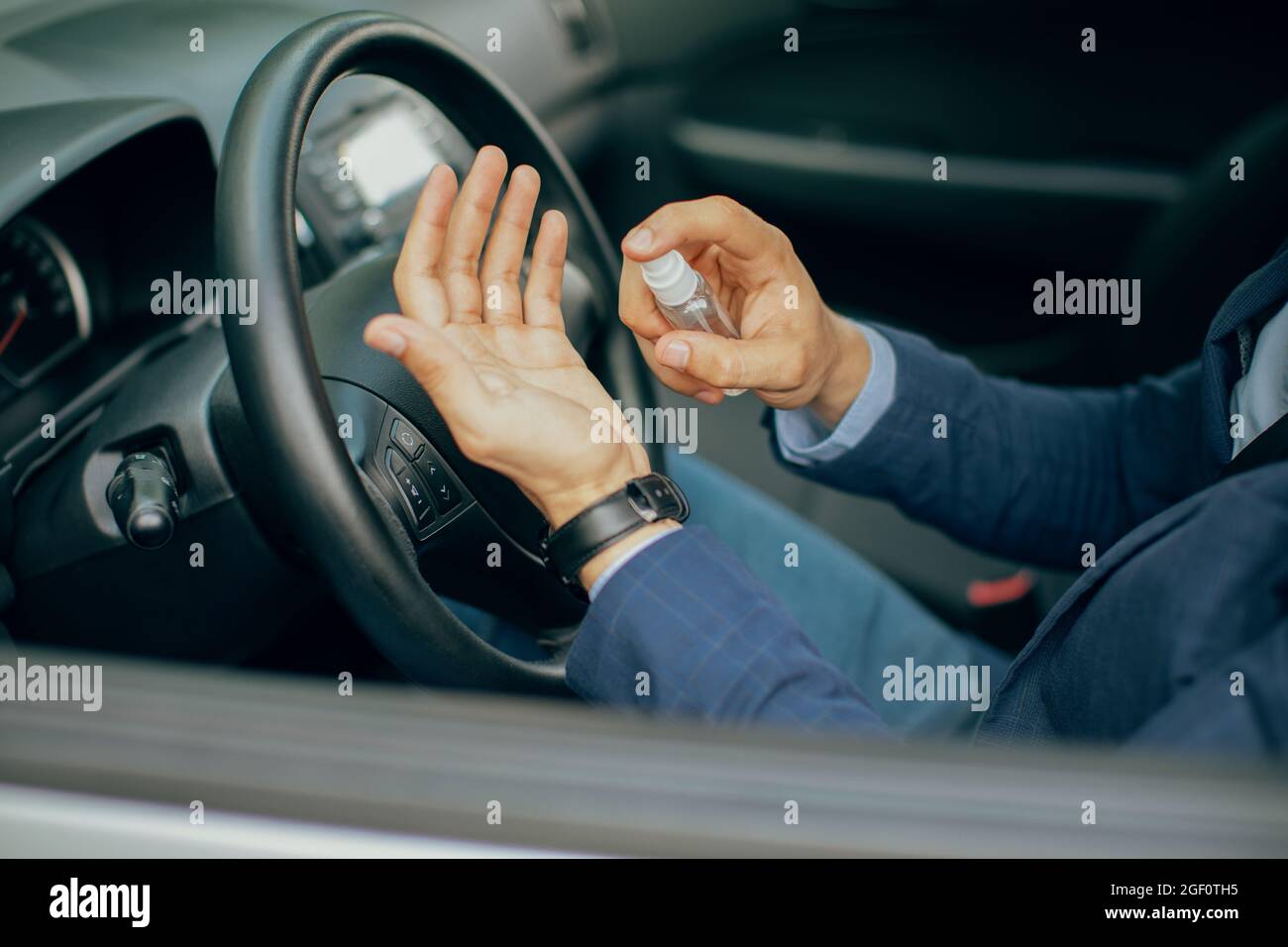 Businessman using disinfectant spray while sitting in car Stock Photo