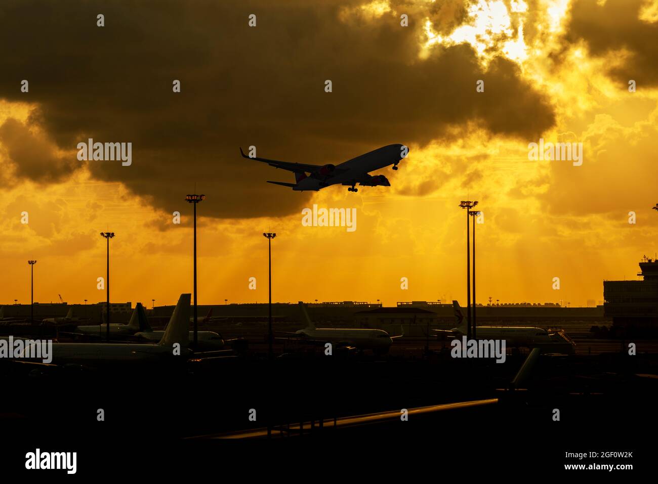 A silhouette of an airplane takes off from the airport with a cloudy ...