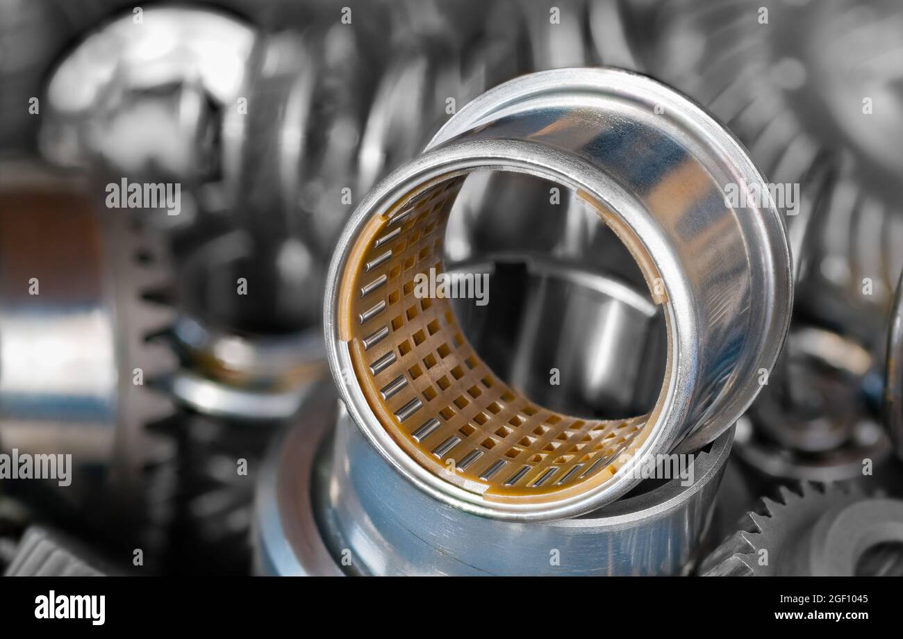 Closeup of needle roller bearing with plastic cylindric cage in steel bushing. Pile of hardware
