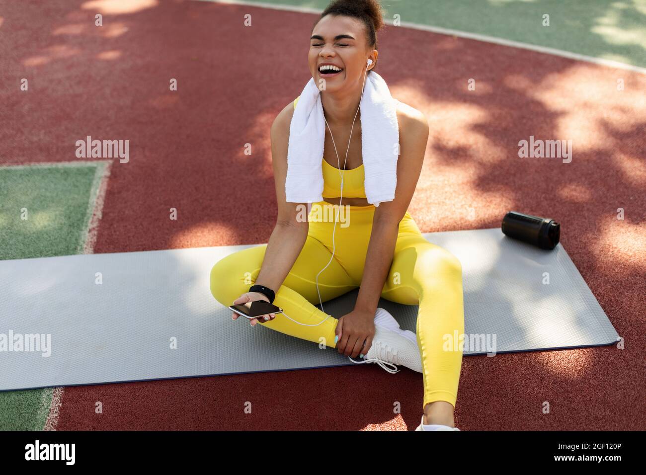 Sporty black woman in yellow sportswear listening to music Stock Photo ...