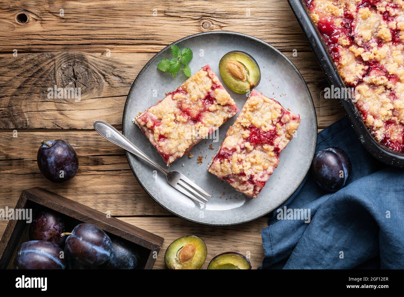 Juicy plum pie slices with crunchy streusel topping on rustic wooden background Stock Photo