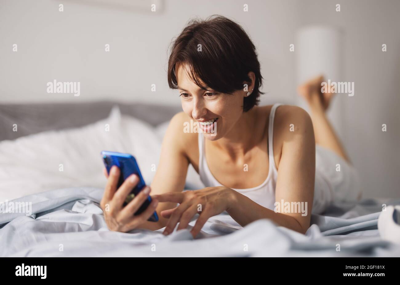 Woman using smartphone in bed Stock Photo