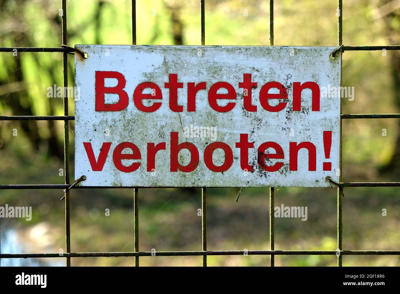A sign in German "Betreten verboten" meaning "Entry forbidden" is fixed on a metal mesh Stock Photo