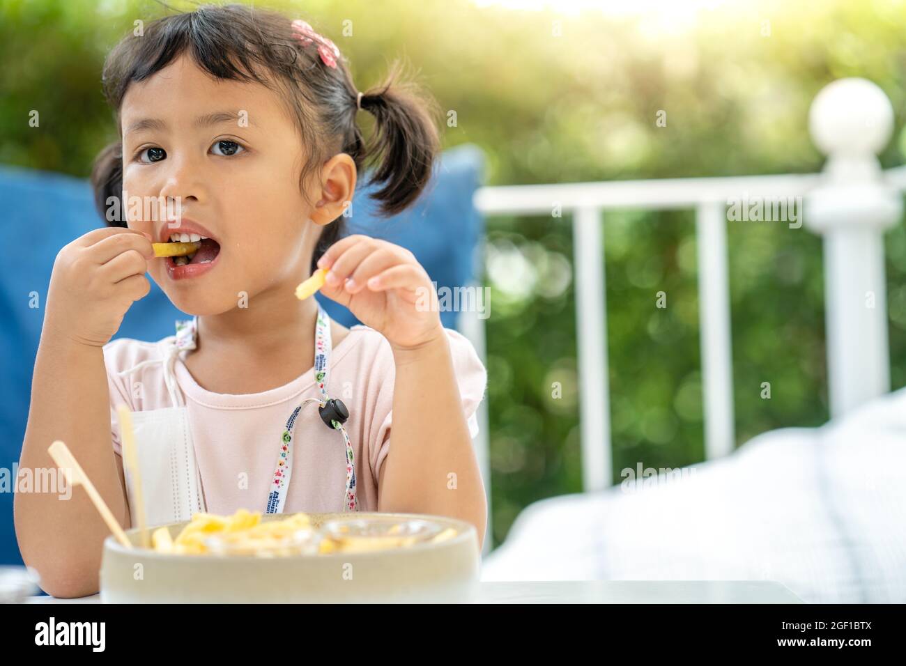 A cute little Thai girl eating French fries Stock Photo