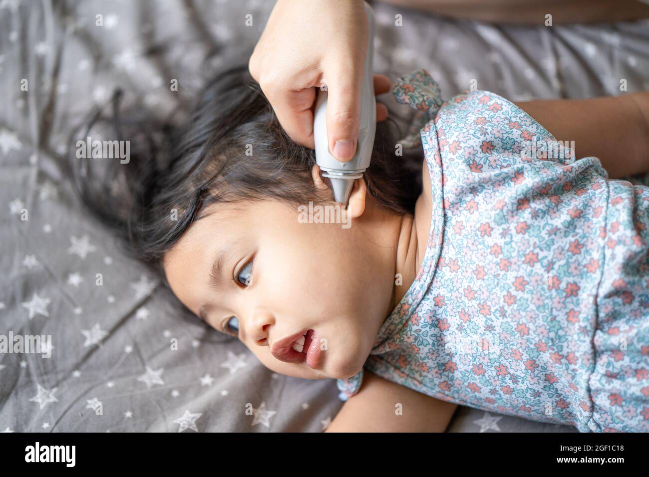 A mother measuring the temperature of her daughter from the ea Stock Photo
