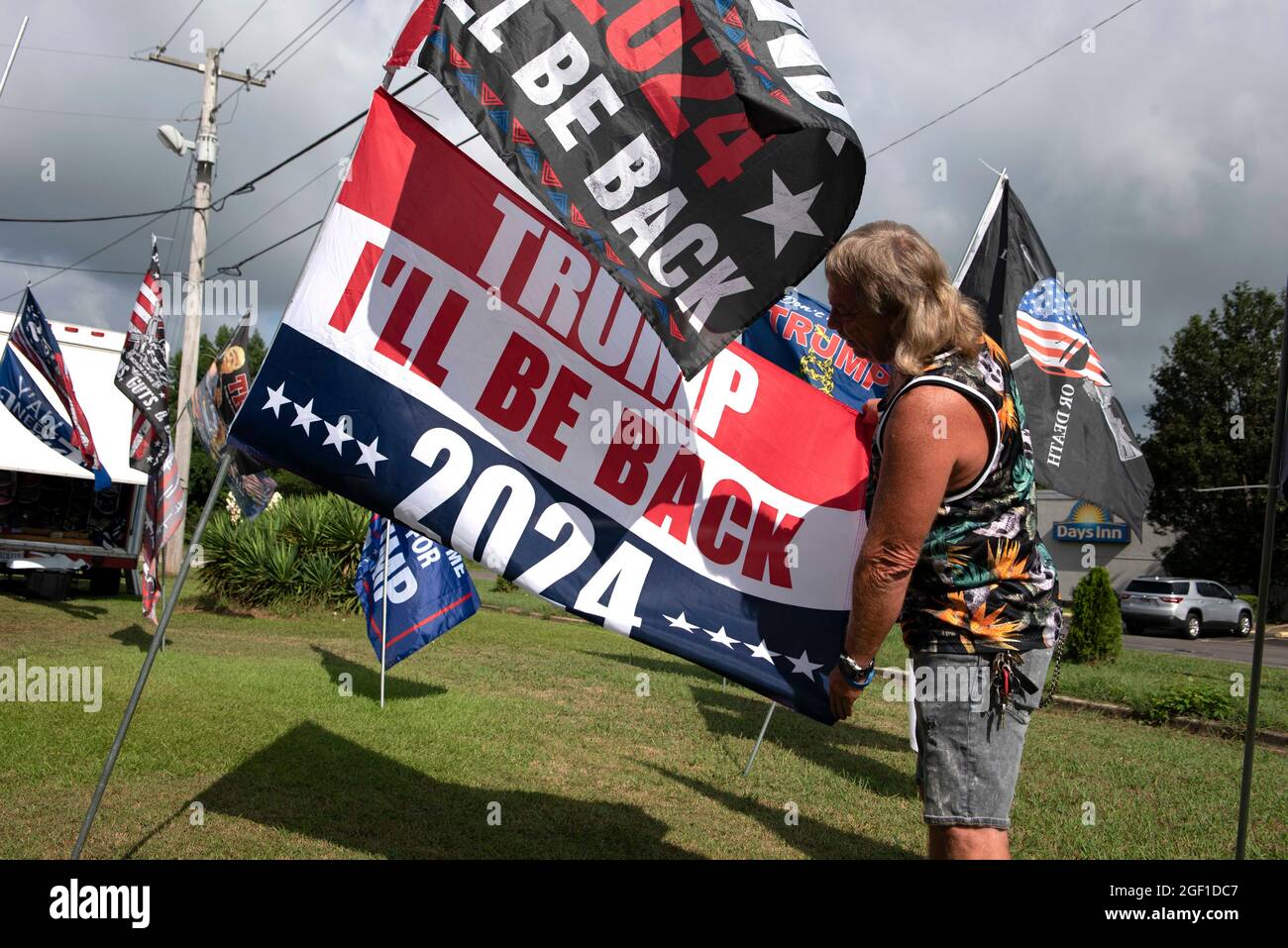 Cullman, Alabama, USA. 22nd Aug, 2021. Unofficial campaign flags and buttons for former President Donald Trump are consistent sellers at a roadside vendor tent in northern Alabama, where a massive political rally Saturday night drew a crowd of several thousand supporters.Pictured: A supporter examines a 2024 Trump campaign flag promising 'IÃll Be Back. (Credit Image: © Robin Rayne/ZUMA Press Wire) Stock Photo